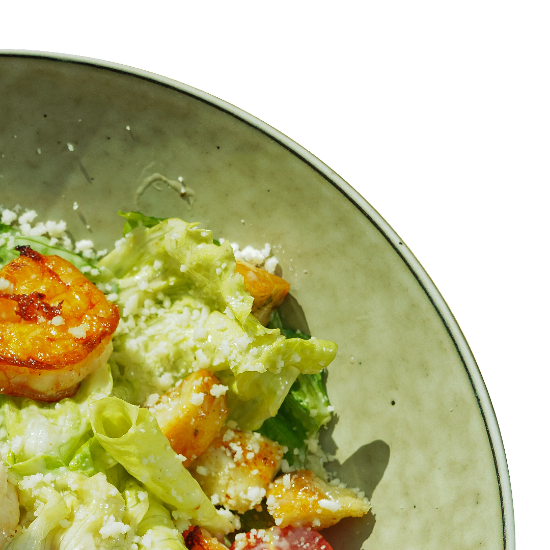 Salad with shrimp, lettuce, avocado, and cheese on a plate.