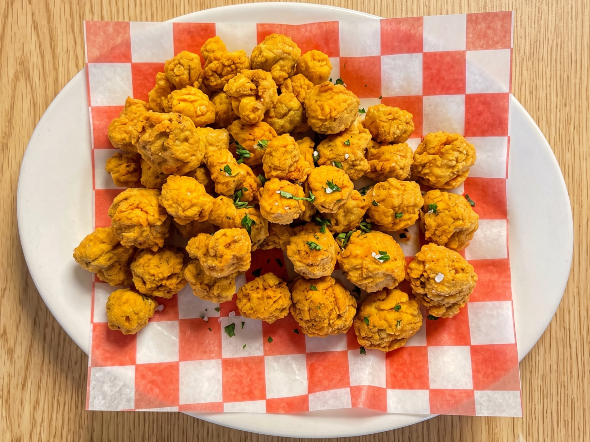 Crispy fried cauliflower on red checkered paper on a plate.
