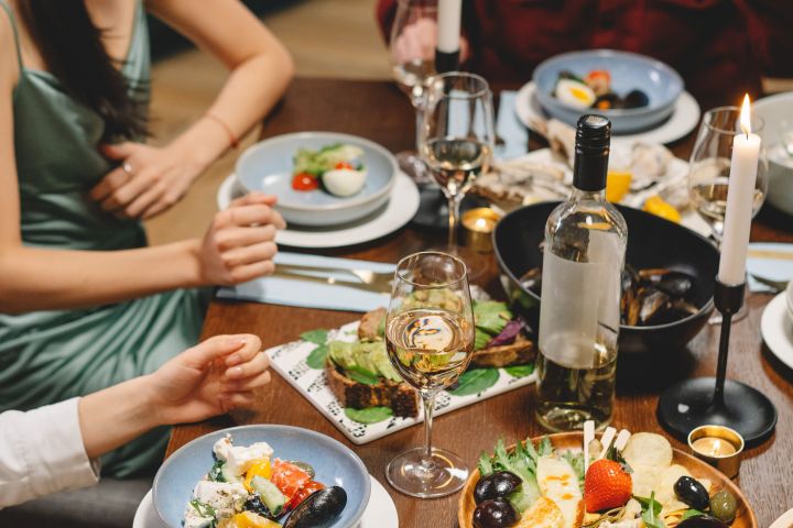 Group of people enjoying a candlelit dinner with salads and wine.