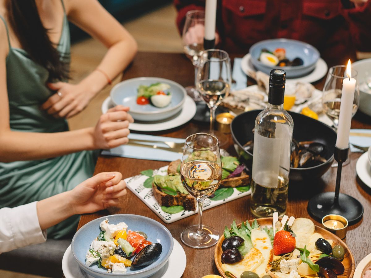 Group of people enjoying a candlelit dinner with salads and wine.