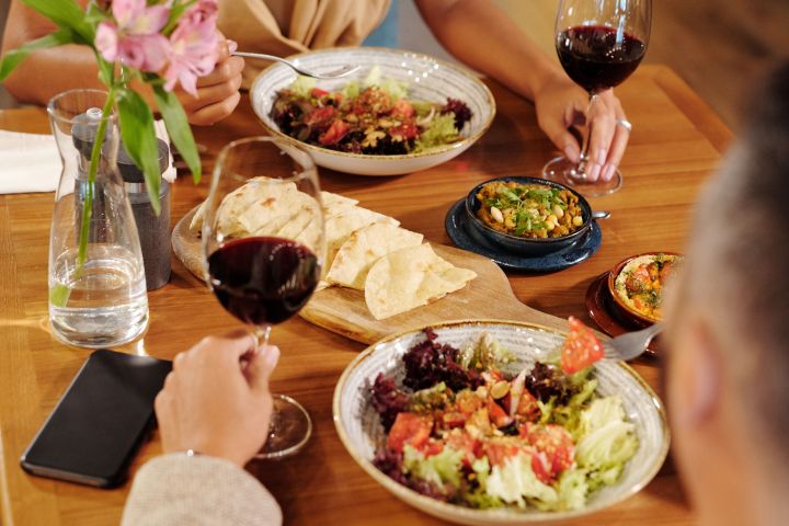 Two people dining with wine, salads, and flowers on the table.