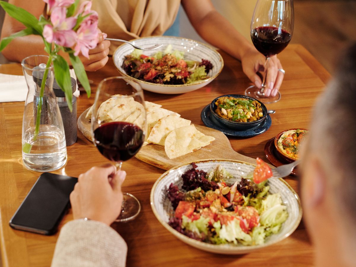 Two people dining with wine, salads, and flowers on the table.
