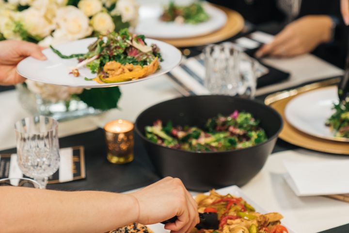 Group dining with plates of gourmet food on a table.